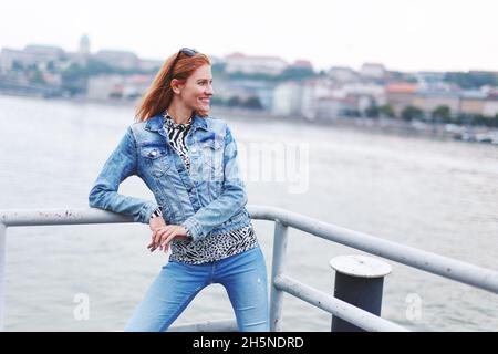 Giovane rossa caucasica alla moda donna toothy sorridente al lungofiume Foto Stock