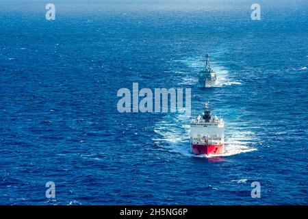 OCEANO ATLANTICO (ott 26, 2021) il rompighiaccio polare USCGC Healy (WAGB 20) e il cacciatorpediniere di missili guidati di classe Arleigh Burke USS Jason Dunham (DDG 109) effettuano un esercizio di passaggio. Healy sta circumnavigando il Nord America a seguito di un transito di passaggio del nord-ovest e di un sostegno alla ricerca scientifica nell'Artico. Jason Dunham opera nell'Oceano Atlantico a sostegno delle operazioni navali per mantenere la stabilità e la sicurezza marittima per garantire l'accesso, scoraggiare l'aggressione e difendere gli Stati Uniti, alleati e partner di interesse. (STATI UNITI Foto della Marina di Seaman Theoplis Stewart II/Rele Foto Stock