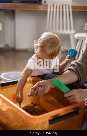 Famiglia entusiasta che gioca a casa sandbox cinetica uso di legno ecologico giocattoli godendo il tempo libero Foto Stock