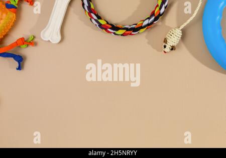 Diversi accessori multicolore per la cura degli animali: Ciotola, ossa, palle, snack, mouse su sfondo beige. Accessori in gomma e tessuto per cani e gatti. Foto Stock