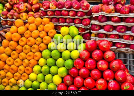 Arance verdi, mele e melograni rossi sono ordinatamente disposti. Frutta in vendita per le strade di Chennai (Madras), India. Gennaio 2018 Foto Stock