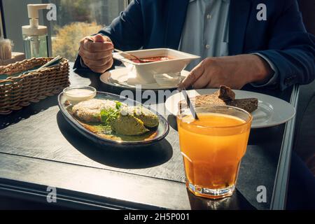 Un giovane uomo d'affari che mangia il pranzo in un caffè, un uomo in una giacca sta pranzando ad un tavolo nero. Pausa pranzo Foto Stock