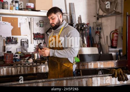 Uomo che prepara la saldatrice al lavoro Foto Stock