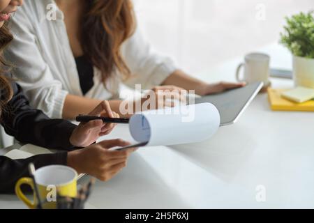 Immagine ritagliata di due colleghi che lavorano insieme per analizzare i dati e pianificare il piano finanziario dell'azienda. Foto Stock