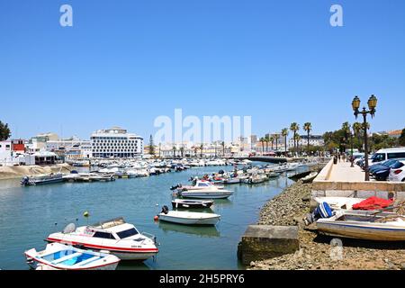 Piccole barche a motore ormeggiate nel porticciolo con edifici sul lungomare sul retro, Faro, Algarve, Portogallo, Europa. Foto Stock