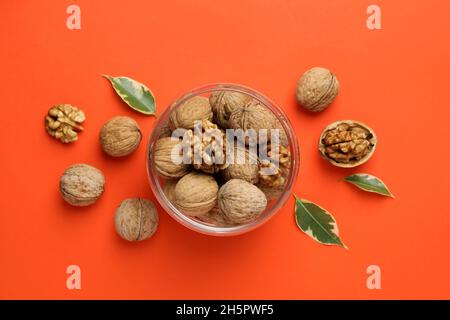 Noci in vaso di vetro su sfondo arancione Foto Stock
