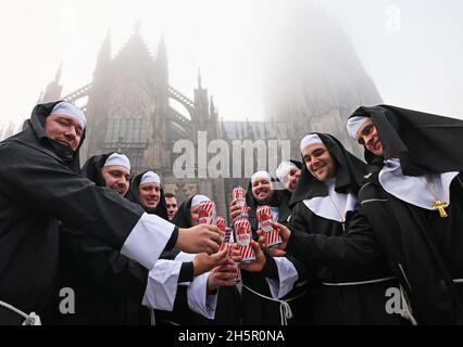 Colonia, Germania. 11 Nov 2021. I carnivalisti vestiti da monache celebrano di fronte alla cattedrale. La nuova stagione di carnevale è iniziata nelle condizioni di Corona. Il 11.11. È celebrato quest'anno di nuovo in presenza. Credit: Oliver Berg/dpa/Alamy Live News Foto Stock