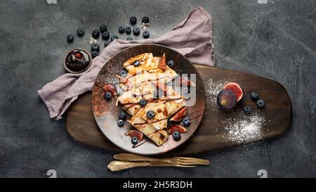 Crepes dolce con fichi e cioccolato su sfondo grigio. Concetto di cibo fatto in casa. Vista dall'alto, disposizione piatta, spazio di copia Foto Stock