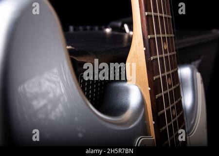 Amplificatore elettrico per chitarra e chitarra in argento su sfondo nero. Foto Stock