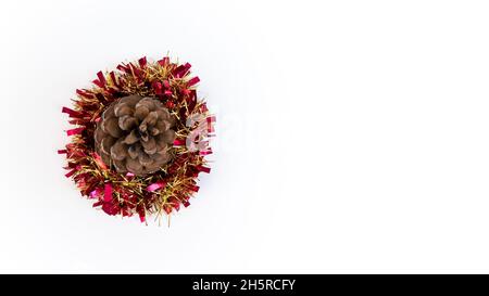 Bellissimo fiore pinecone con un Natale tinsel per decorazioni tradizionali in inverno. Coni di pino xmas e garland nastro isolato su backgrou bianco Foto Stock