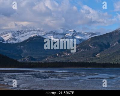 Splendida vista sul lago Jasper (fiume Athabasca) nelle Montagne Rocciose, Alberta, Canada in autunno con colline coperte di alberi e vette innevate. Foto Stock