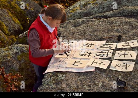 BLATNO, REPUBBLICA CECA - CIRCA OTTOBRE 2021: Una bambina si pratica scrivendo calligrafia all'esterno sulle rocce. Foto Stock