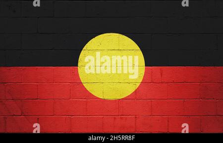 Bandiera aborigena australiana dipinta su un muro di mattoni. Foto Stock
