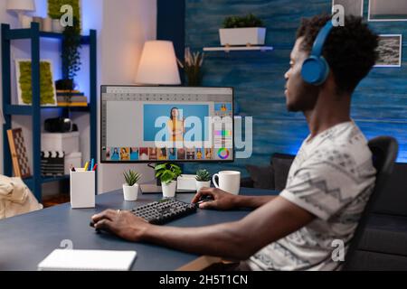 Editor afro-americano con cuffie che ritoccano le foto creative. Fotografo che lavora a fotoritocco su computer utilizzando un software professionale di post-produzione. Fotografia digitale sullo schermo Foto Stock