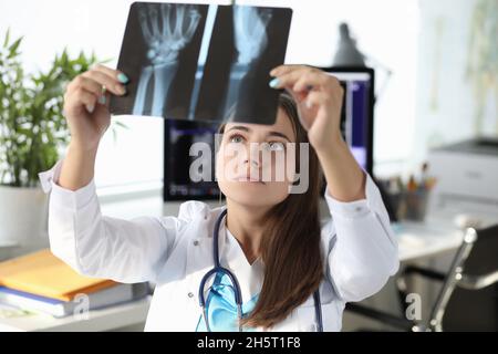 Medico donna che guarda raggi di mano in clinica Foto Stock