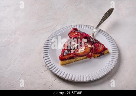 Ravvicinato il pezzo di torta di prugne su un piatto leggero con una lama a spalla. Spazio di copia Foto Stock