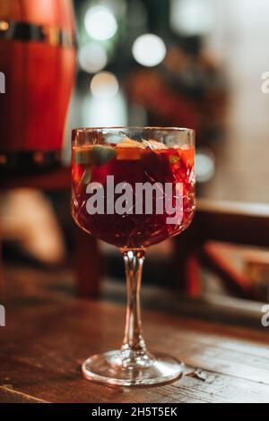 Bicchiere di cristallo di VIN brulé caldo con frutta fresca e spezie su un tavolo di legno Foto Stock