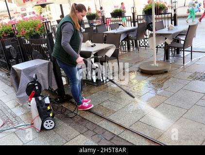 Cracovia. Cracovia. Polonia. Donna lavoratore lavaggio il pavimento in ristorante giardino estivo con lavatrice a pressione. Foto Stock