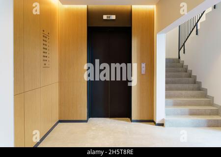 Ascensore nella hall di un edificio di appartamenti. Decorazioni moderne e finiture in legno del piano terra e dell'ingresso. Foto di alta qualità Foto Stock