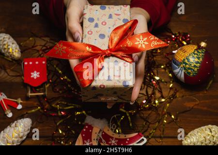 Regalo di Natale nelle mani della donna. Le mani femminili che tengono il regalo di nuovo anno. Sfondo decorazione di nuovo anno Foto Stock