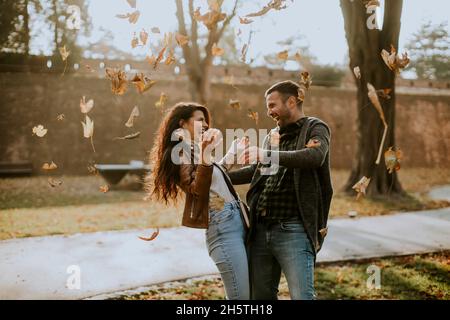 Felice giovane coppia divertirsi con le foglie d'autunno nel parco Foto Stock