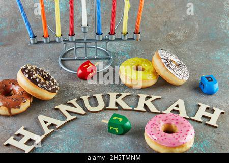 Happy Hanukkah e Hanukkah Sameach - candeliere ebraiche tradizionali con candele, ciambelle e cime rotanti con l'iscrizione Hanukkah. Foto Stock