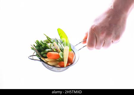 la mano maschio tiene le verdure su uno sfondo bianco. Mangiare sano. Cibo vegano. Cibo crudo Foto Stock