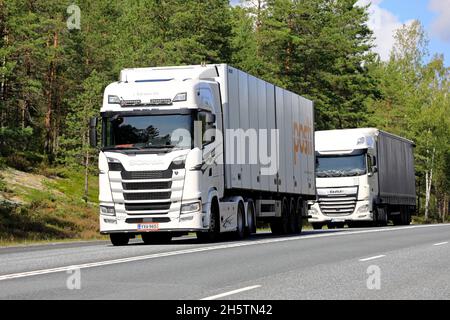 I veicoli semirimorchi bianchi Scania S500 e DAF XF trasportano merci sull'autostrada 3 direzione sud in estate. Ikaalinen, Finlandia. Agosto 12, 2021. Foto Stock