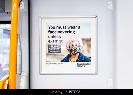 18 aprile 2021 - Poster che dice ai passeggeri di indossare maschere facciali durante la pandemia di coronavirus su un treno della ferrovia sud-occidentale a Waterloo, Londra, Regno Unito Foto Stock