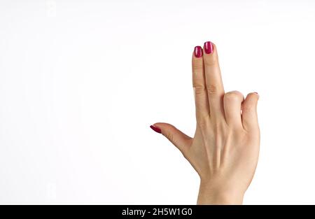 Mano della donna che fa sparare pistola, gesto. Mano pistola gesto su isolato bianco sfondo. Mano donna che punta con due dita. Foto Stock