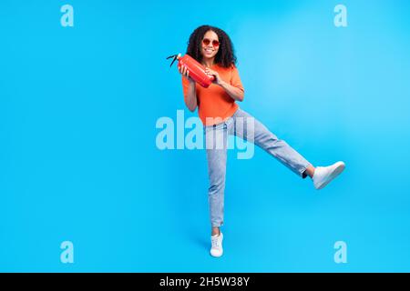 Foto a grandezza naturale della giovane donna africana felice sorriso positivo tenere estintore sicurezza isolato su sfondo blu Foto Stock