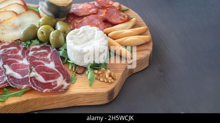 Tapas molto colorate di salumi con formaggio e carni affumicate. Decorata con rucola e noci. Spuntini di vino. Foto Stock