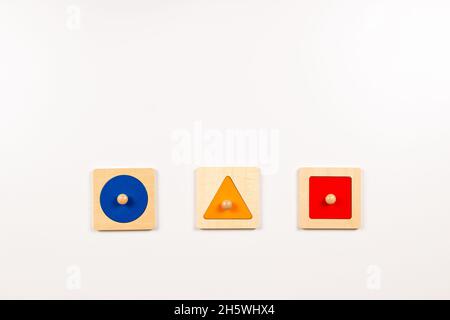 Coloratissimo Montessori in legno materiale sensoriale imparare giocattoli educativi su sfondo bianco. Giocattoli per tavole di selezione di forma geometrica per bambini. Superiore Foto Stock