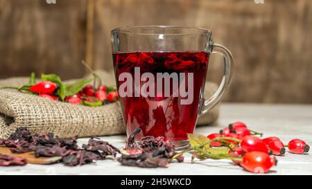 Tè naturale da frutti di bosco di rose su tavole di legno. Trattamento omeopatia da bacche rosse. Foto Stock