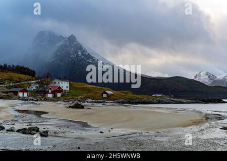 Wetterwechsel über der Bucht von Grøtfjord, Norwegen mit einem Wolkenbruch über den Bergen und schöne Häuser am Strand. Regen, Schneefall Foto Stock