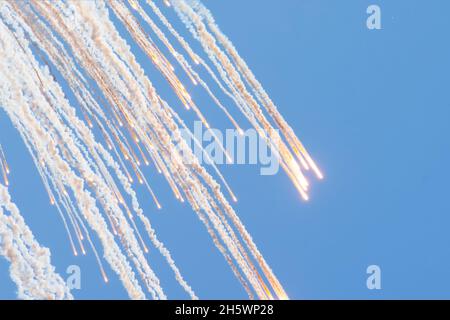 Molte luci che scottano dall'esplosione nel cielo blu lasciano un pennacchio di fumo Foto Stock