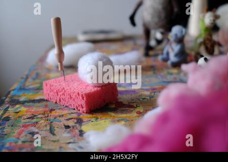 Ago in un cubo feltrato su una spugna rosa. Accessori per feltro ad ago, lana tessitura artigianale fatta a mano da pelo di pecora. . Foto di alta qualità Foto Stock