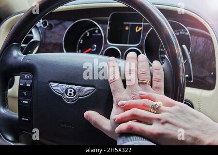 Kiev, Ucraina; 30 gennaio 2014. Bentley Continental Flying Spur. Mani di uomo e donna insieme sul volante. Nelle mani degli anelli di nozze Foto Stock