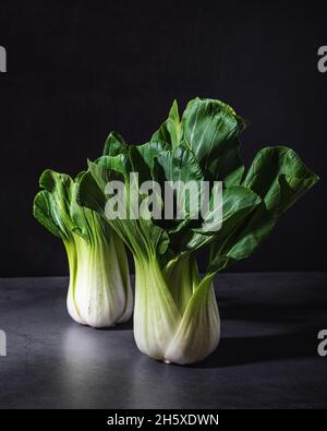 Sano fresco bok choy cavoli foglia vegetale posto su tavola nera su sfondo scuro Foto Stock