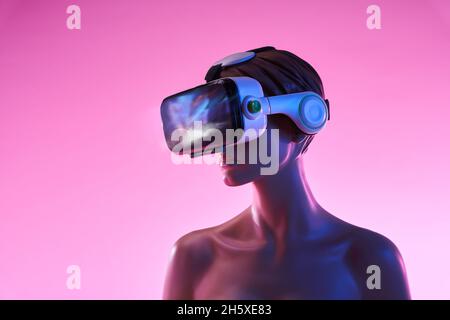Femmina manichino con occhiali VR posizionati su sfondo rosa brillante come simbolo della tecnologia futuristica Foto Stock