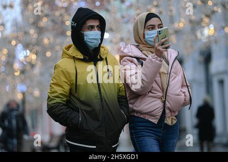 Mosca, Russia. 11 Nov 2021. Le persone che indossano maschere per il viso camminano su una strada a Mosca, in Russia, il 11 novembre 2021. La Russia ha confermato 40,759 infezioni da COVID-19 nelle ultime 24 ore, portando il conteggio nazionale a 8,952,472, il centro ufficiale di monitoraggio e risposta ha detto Giovedi. Credit: Evgeny Sinitsyn/Xinhua/Alamy Live News Foto Stock