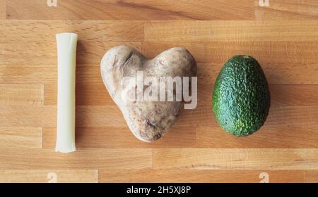 Adoro l'avocado o il messaggio guacamole scritto usando gli alimenti compreso il formaggio della stringa della mozzarella e una patata a forma di cuore su un tagliere di legno. Foto Stock