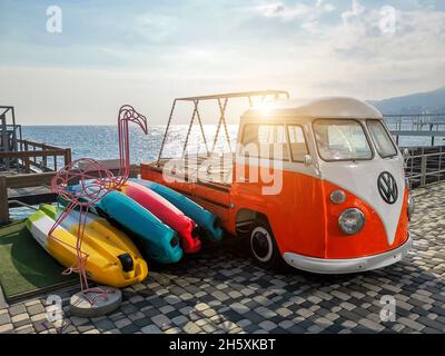 Yalta, Ucraina - Ottobre 31,2021: Vecchio retrò vintage arancio brillante bianco VW T1 bulli camper bus personalizzato come kayak boat rimorchio parcheggiato vicino al mare Foto Stock