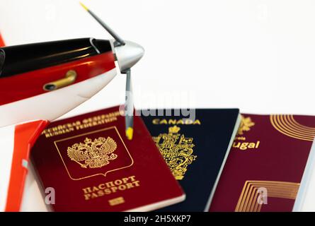 Tre diversi passaporti isolati su bianco. Passaporti canadesi, portoghesi e russi per l'ingresso in diversi paesi. Primo piano, sfocato, selettivo Foto Stock