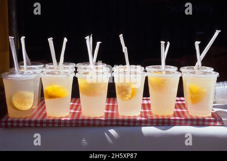 Spicchi di limonata e limone in tazze di plastica con cannucce. Sana bevanda fredda a base di frutta fresca. Bevande fredde con clima caldo. Niente persone. Idratare Foto Stock