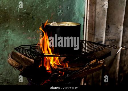 Manioca che viene cucinata in padella di ferro con fuoco di legno sulla parte superiore di una griglia. Salvador Bahia Brasile. Foto Stock