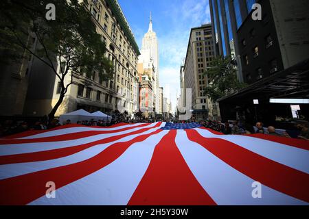 New York, N.Y/USA – 11 novembre 2021: I volontari hanno una bandiera americana drappeggiato sulla Fifth Avenue durante la Veterans Day Parade a New York il 11 novembre 2021. (Credit: Gordon Donovan/Alamy Live News) Foto Stock
