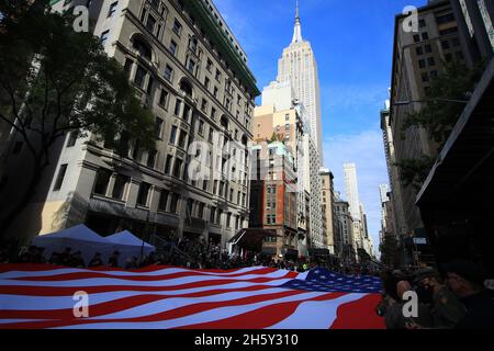New York, N.Y/USA – 11 novembre 2021: I volontari hanno una bandiera americana drappeggiato sulla Fifth Avenue durante la Veterans Day Parade a New York il 11 novembre 2021. (Credit: Gordon Donovan/Alamy Live News) Foto Stock