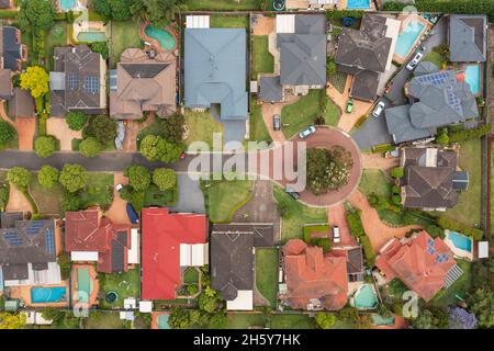 Vista aerea dall'alto in basso di una strada residenziale con case, piscine e giardini nel sobborgo esterno di Sydney di Kellyville, NSW, Australia. Foto Stock