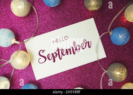 Ciao settembre testo tipografico con pallina LED in cotone su sfondo rosa glitter Foto Stock